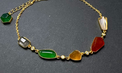 Jade bracelet mixing with gold bracelet featuring multiple gemstones in green gray yellow red white
